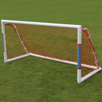 A football goal sits on a grassy field. The goal is white with a red net, and the word "DIAMOND" is visible on one post.