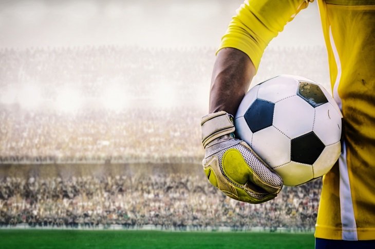 A goalkeeper holds a football