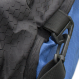 A dark grey bag's textured fabric is shown with a black strap and a clasp attached. The bag's zipper is visible, and it is partially folded to reveal a blue lining.